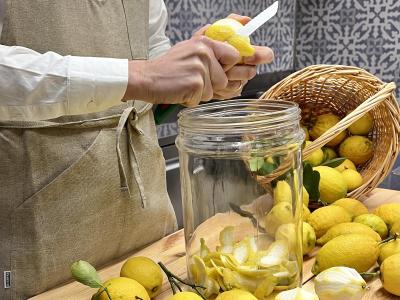 Person peels lemons in kitchen, filling a jar.