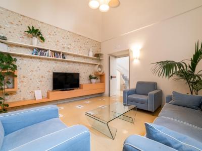Salotto moderno con divani blu, tavolo in vetro e piante.