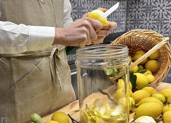 Person peels lemons in kitchen, filling a jar.